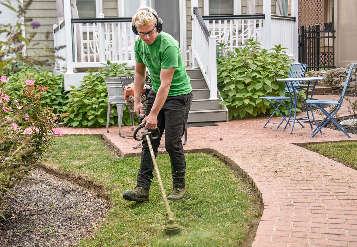 Worker edging lawn with weed eater